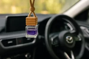 Close-up do interior de um carro decorado com elementos delicados e femininos, com um aromatizador pendurado no retrovisor.